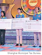 [Pu Jian, center, holds a check after her win on the Shanghai tax bureau's 'Happy Draw' show.]